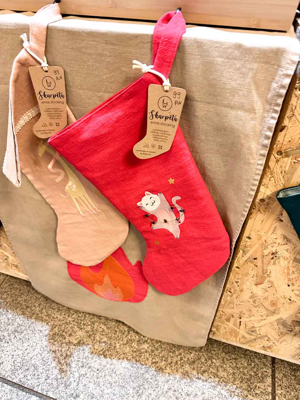 Handmade Christmas stockings, including a red one with a white cat, hanging on display at a craft stall