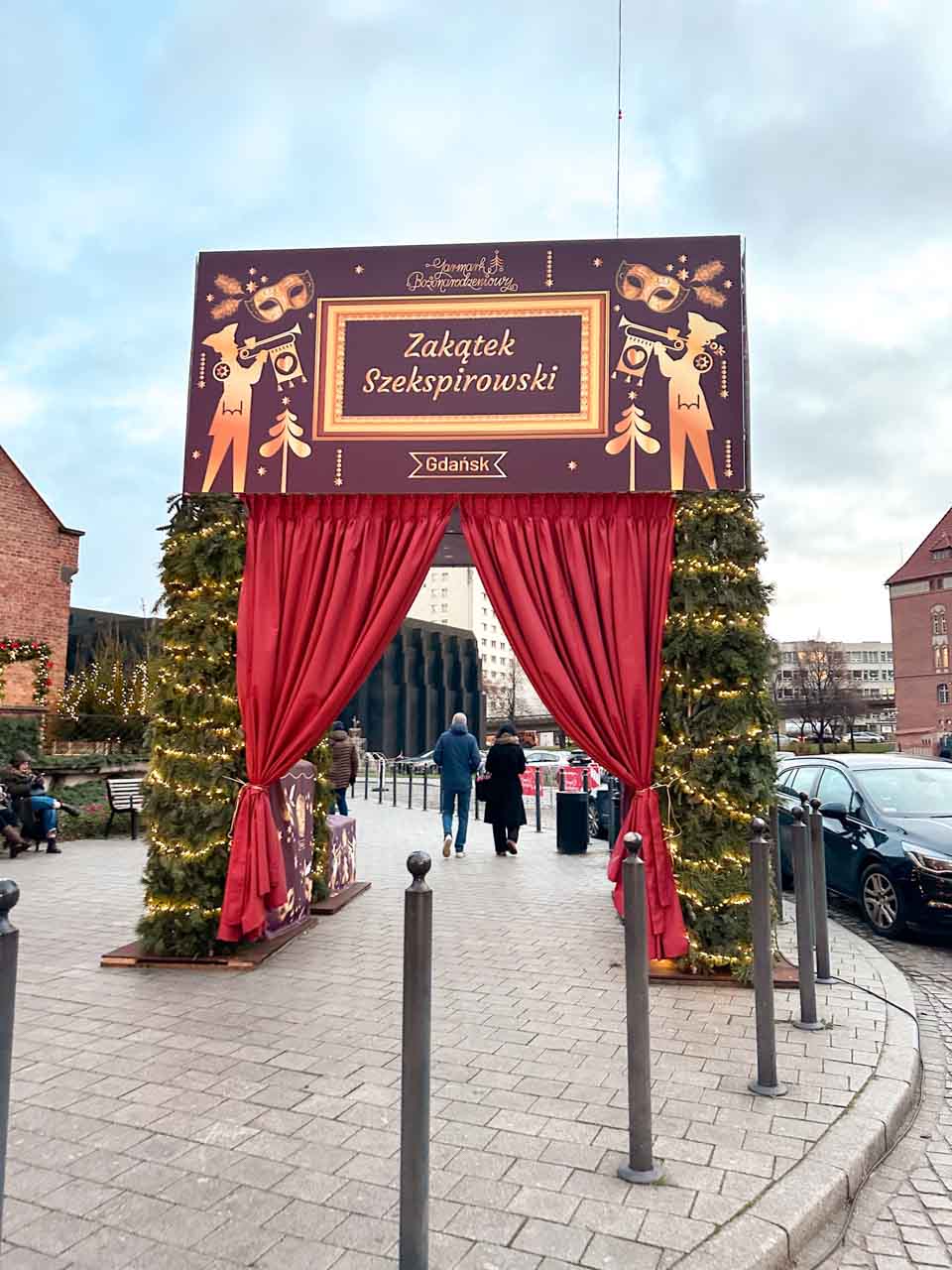 The Shakespeare Corner entrance at the Gdańsk Christmas Market, framed by red curtains and festive greenery