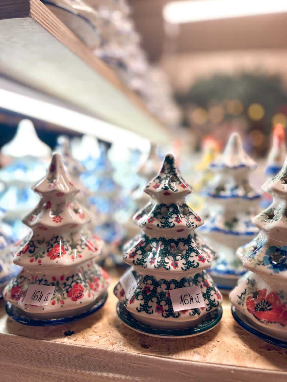 Painted ceramic Christmas trees with floral patterns on a wooden stall display at the Krak&oacute;w Christmas market