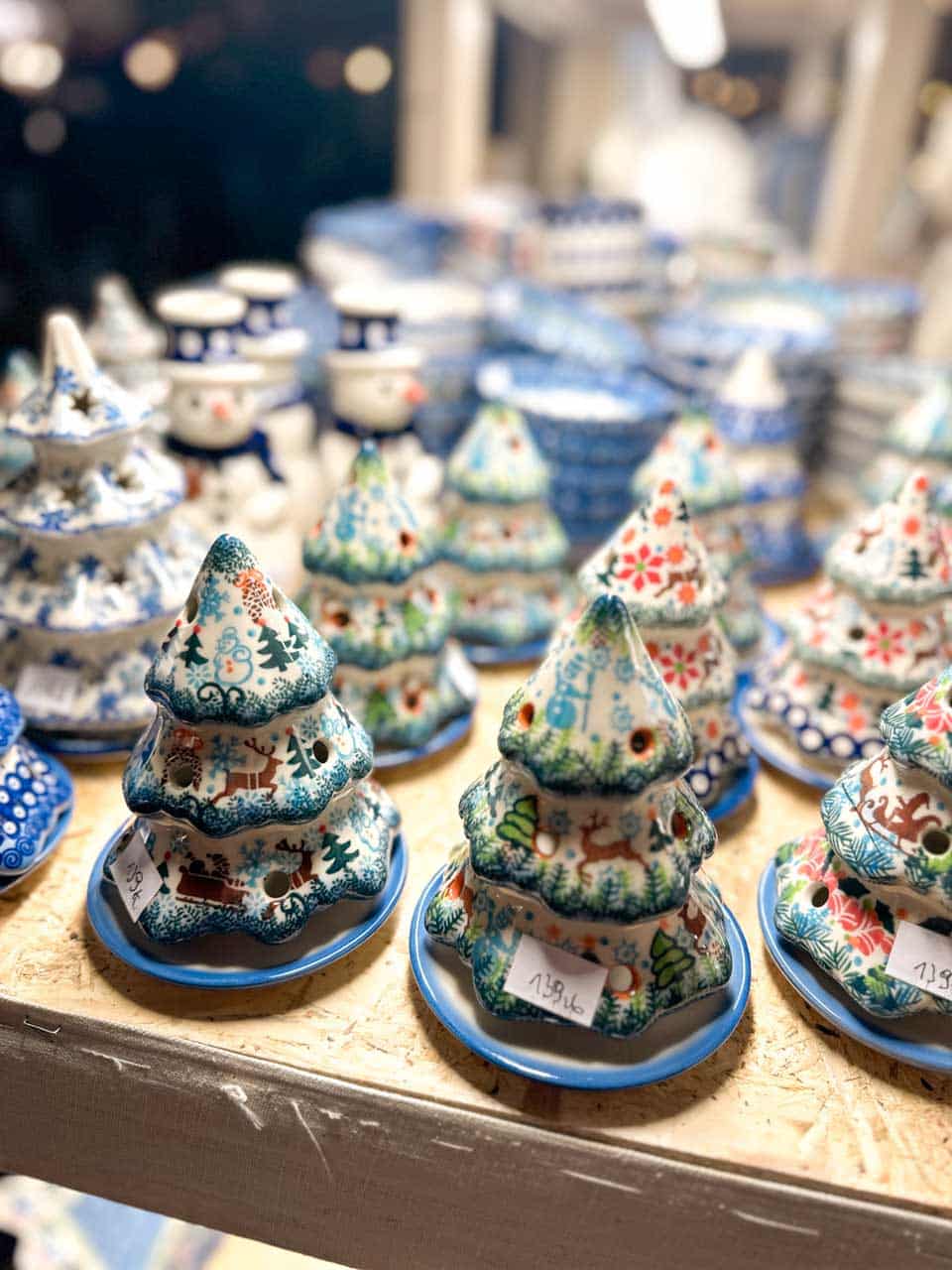 Polish pottery Christmas trees with reindeer and snowflake patterns displayed on a wooden shelf at the Krak&oacute;w Christmas market