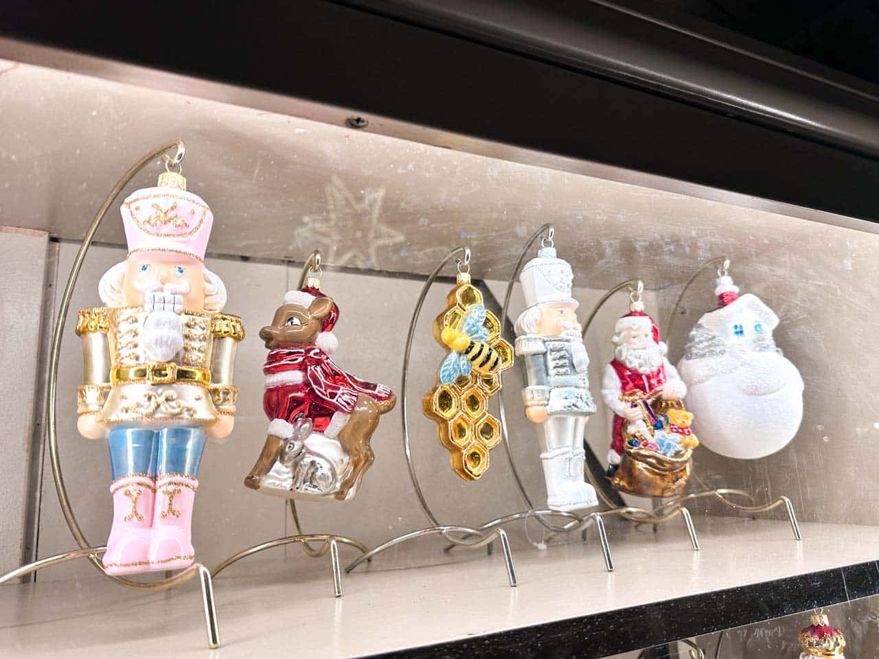 Glass Christmas ornaments including nutcrackers, Santa, and a deer lined up on display hooks at the Christmas market in Krak&oacute;w
