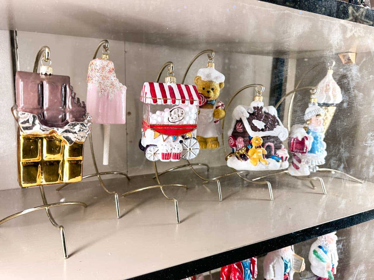 Whimsical glass ornaments shaped like sweets, a gingerbread house, and other festive designs on display at the Christmas market in Krak&oacute;w