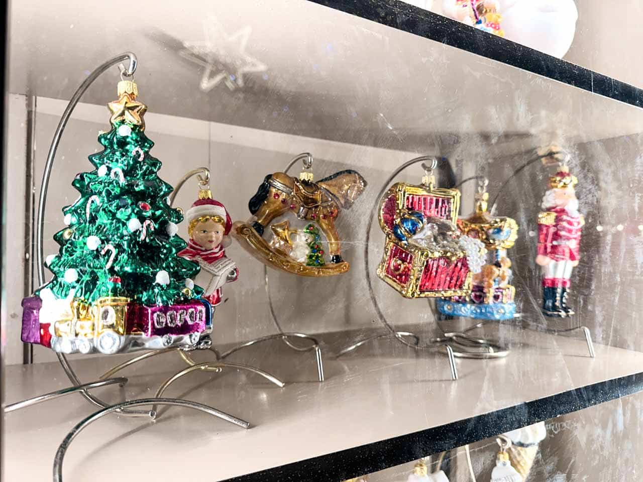 Colourful glass tree decorations shaped like a Christmas tree, rocking horse, and toy box on display at the Krak&oacute;w Christmas market