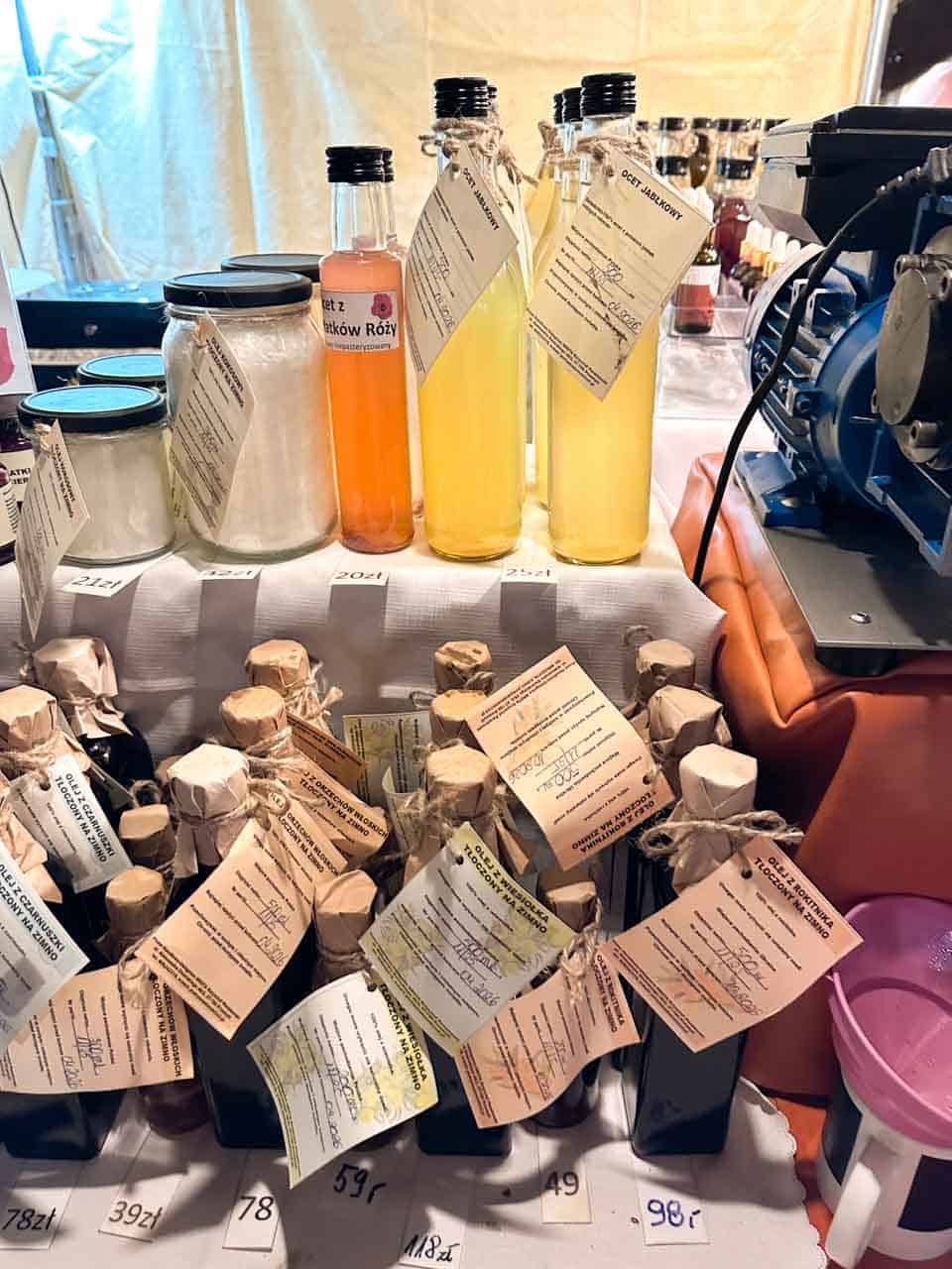 Bottles of homemade vinegar and oil with handwritten labels displayed alongside jars of salt