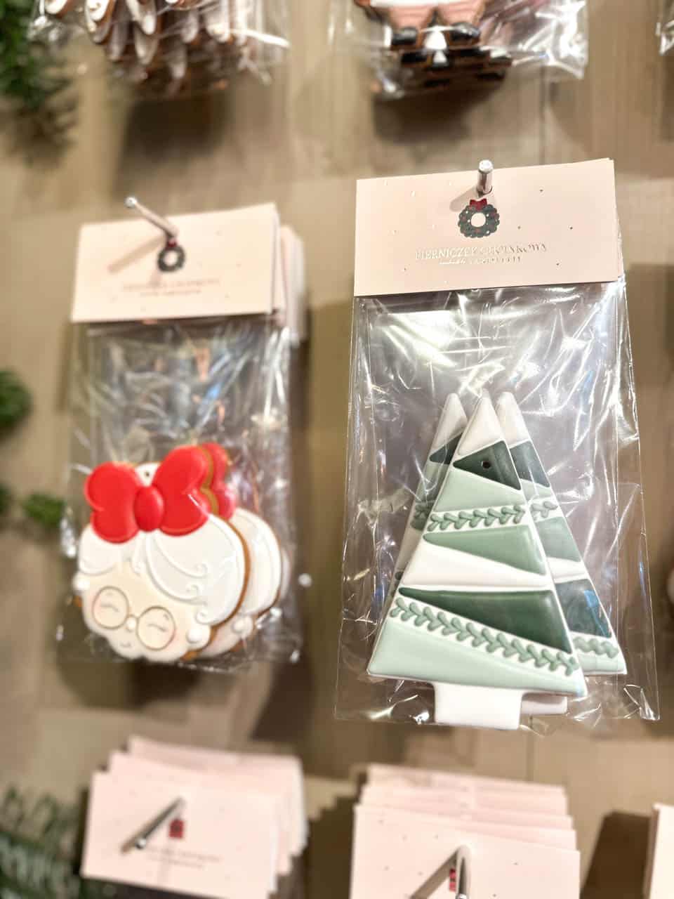 Iced biscuits shaped like a smiling granny and minimalist green tree, hanging on a festive market stall display in Krak&oacute;w