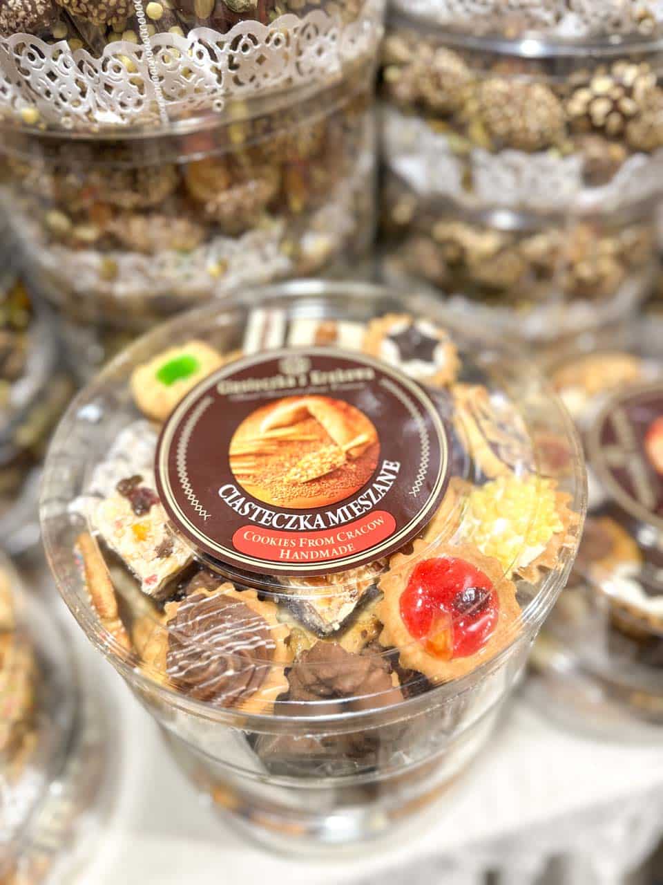 A round plastic box filled with assorted handmade cookies from Krak&oacute;w, topped with a label reading 'Ciasteczka Mieszane'