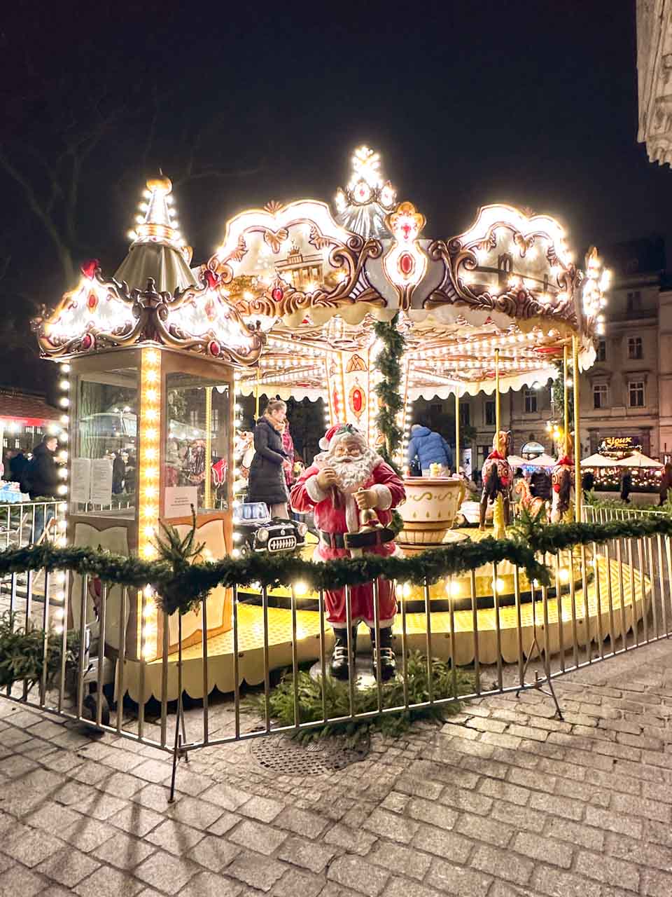 A traditional carousel lit up at night with Santa decorations and children enjoying the ride at the Main Market Square in Krak&oacute;w, Poland