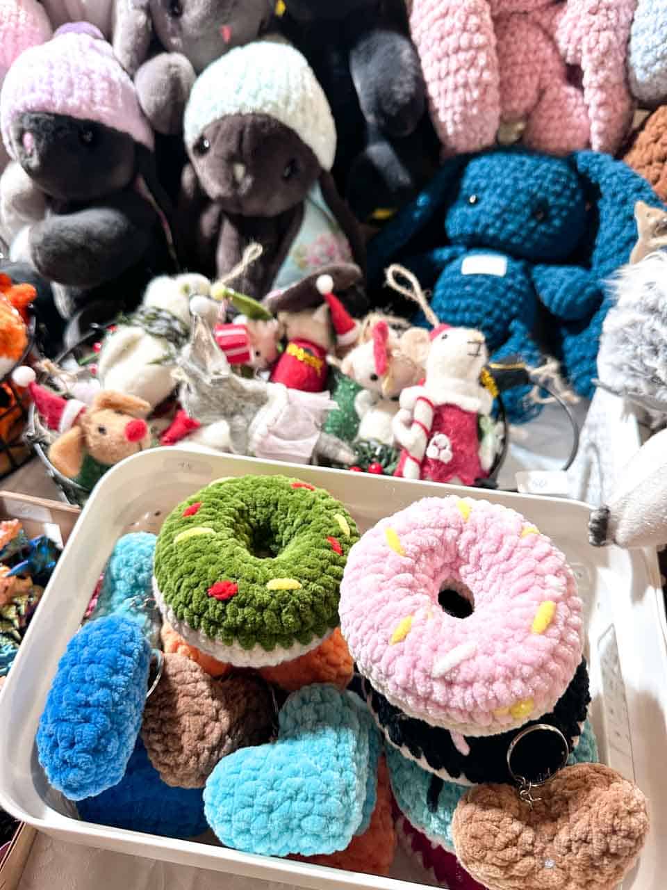 Colourful plush toys at a Christmas stall in Krak&oacute;w, including crocheted donut keyrings and soft teddy bears in winter hats