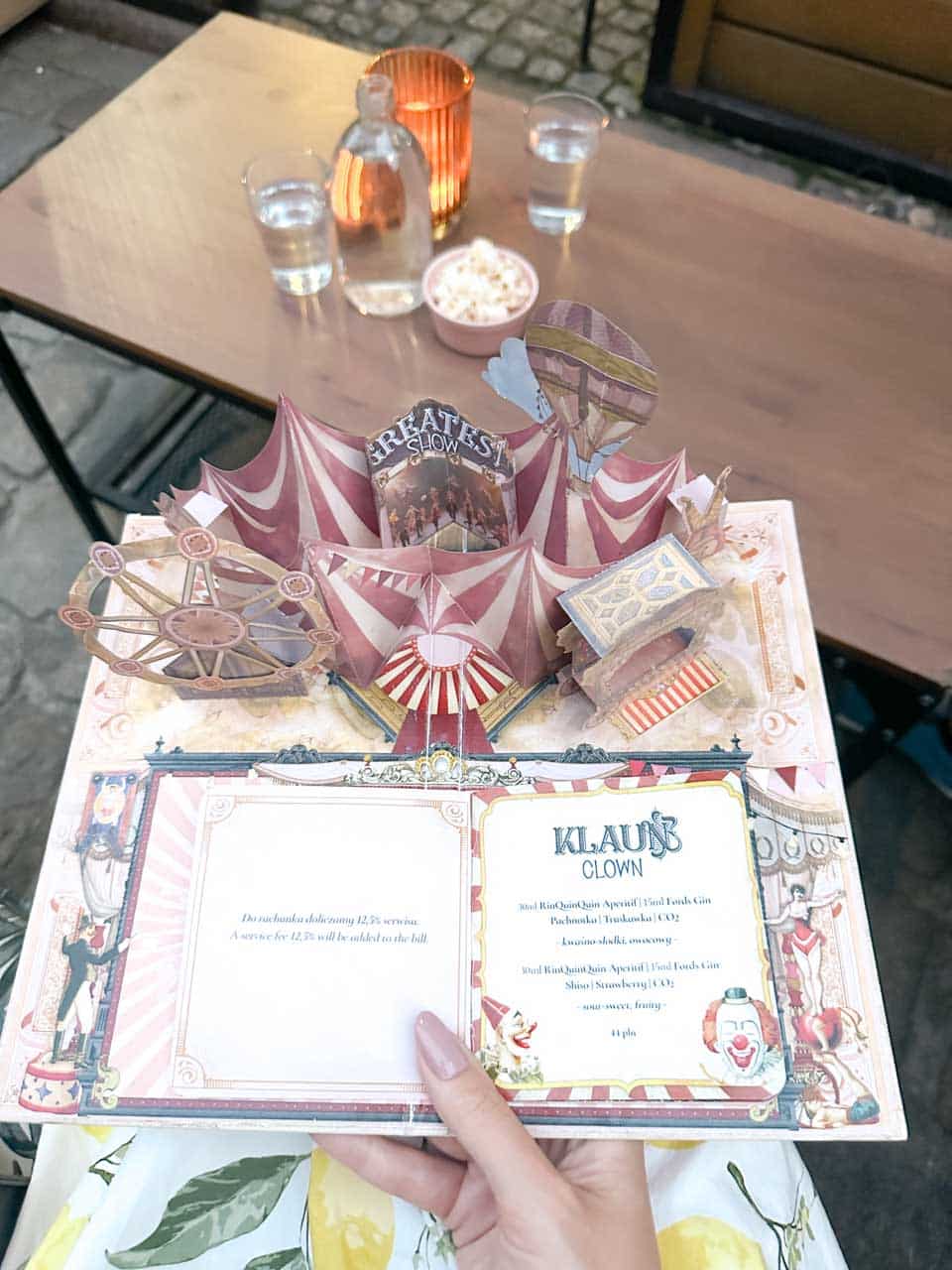 A pop-up cocktail menu shaped like a circus tent with colourful details and a &ldquo;Clown&rdquo; drink description at Flisak '76 in Gdańsk, Poland
