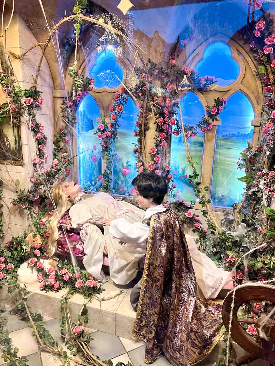 Sleeping Beauty fairy tale scene with a prince, a rose-covered room, and a spinning wheel