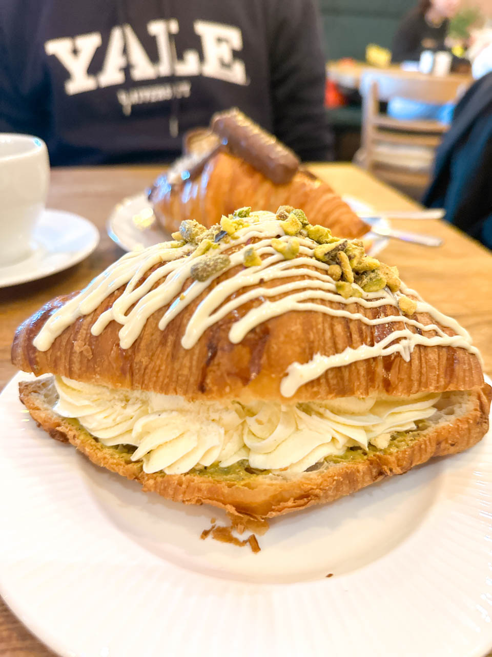 Pistachio cream croissant topped with icing and crushed pistachios on a plate at Cafe Antidotum in Gdańsk