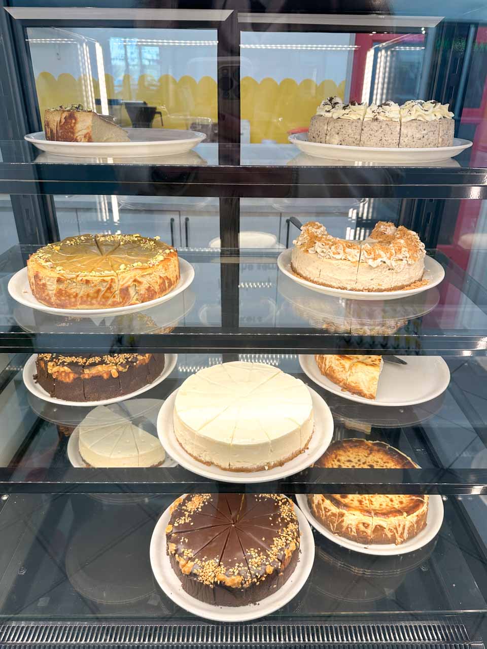 Cake display fridge at The Sernik in Gdańsk filled with cheesecakes on white plates