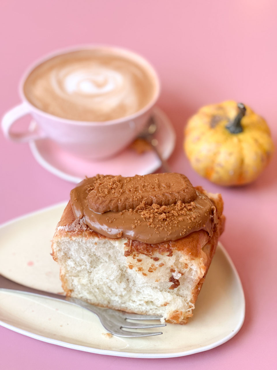 Fluffy bun topped with Biscoff spread and a Biscoff biscuit, served with coffee and a decorative mini pumpkin at Bez&oacute;wka in Gdańsk