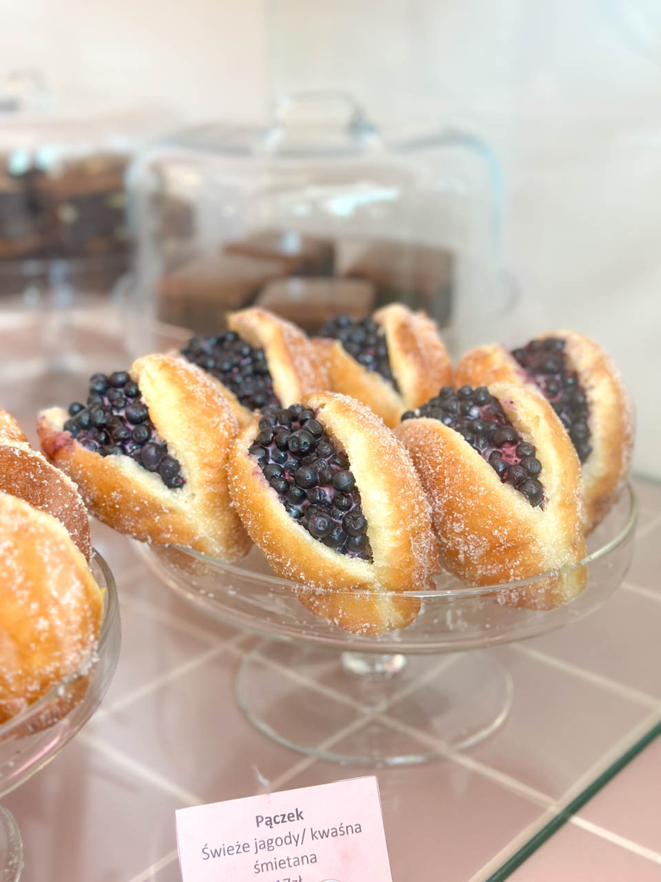 Sugar-coated doughnuts filled with bilberries and cream in a glass bowl display at Bez&oacute;wka in Gdańsk