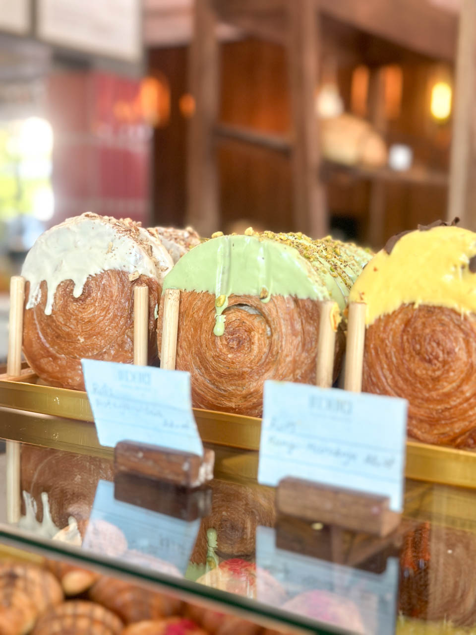 New York roll pastries with different toppings lined up in a pastry case at Le Delice in Gdańsk
