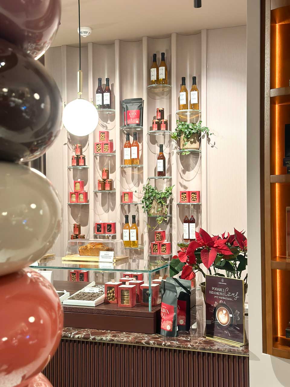 Display of coffee beans, fruit liqueurs, and sweets arranged on wall shelves inside Kaiser Patisserie in Gdańsk