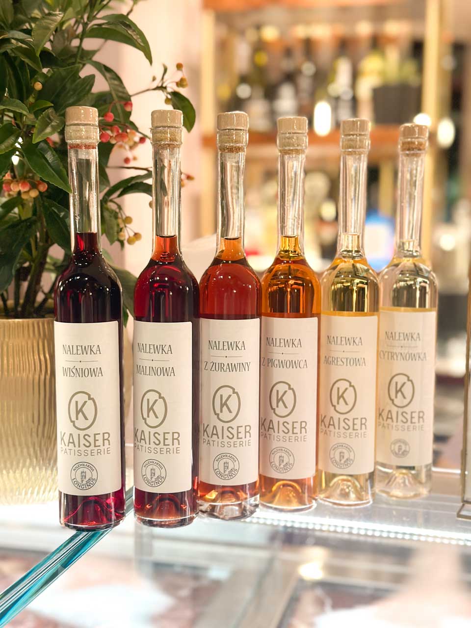 Row of flavoured nalewka liqueur bottles displayed on a glass shelf at Kaiser Patisserie in Gdańsk, Poland