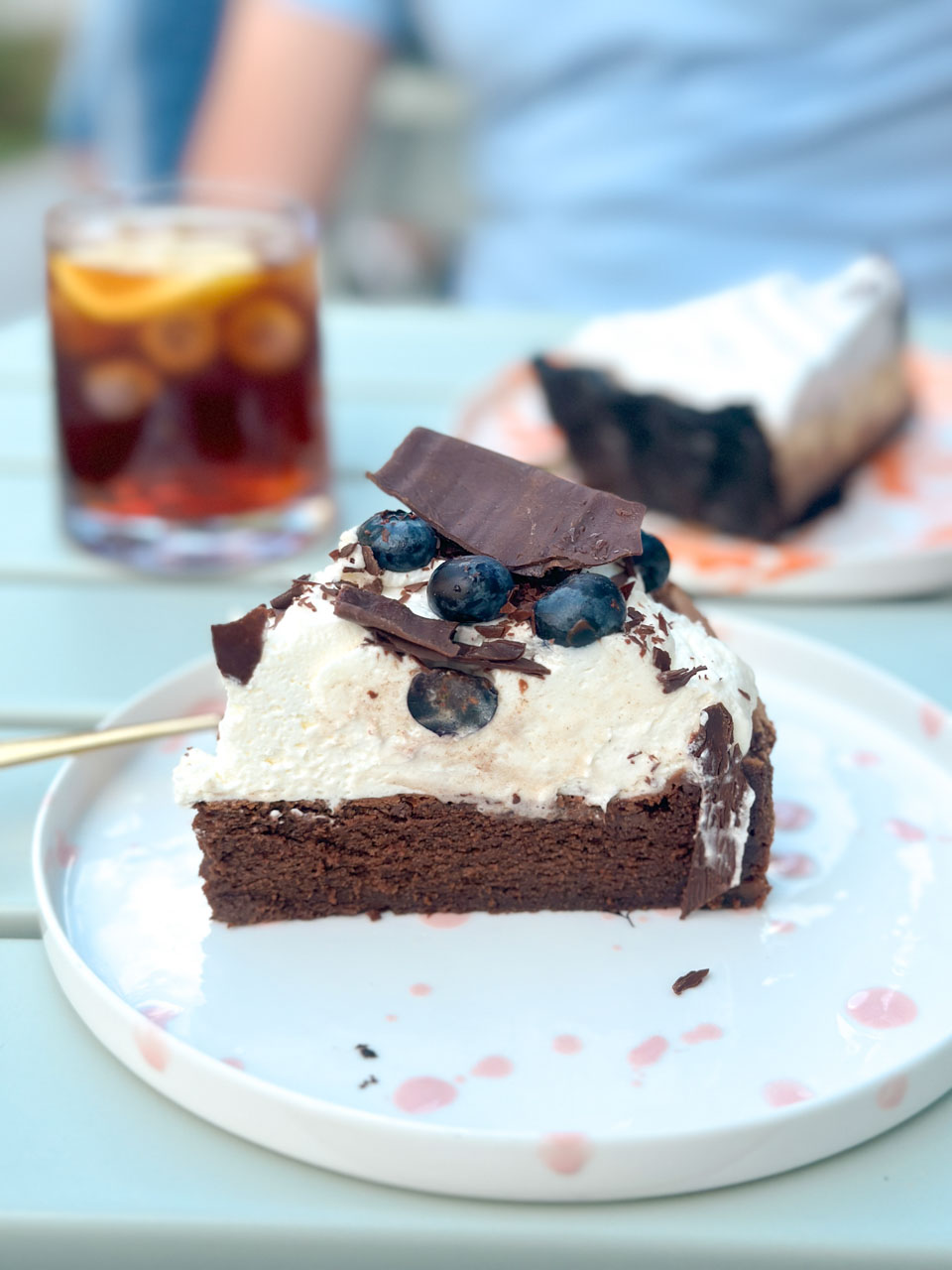 Chocolate cake slice topped with cream and blueberries on a plate