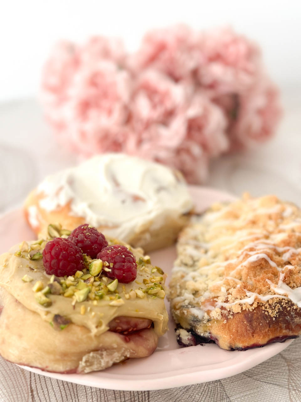 Plate of sweet buns with pistachio cream, raspberries, and crumble topping
