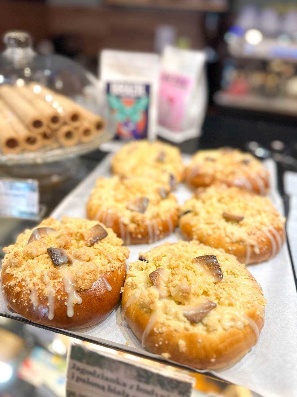 Bilberry buns with icing, crumble, and toasted white chocolate chips arranged on a bakery tray at Cafe Antidotum in Gdańsk, Poland