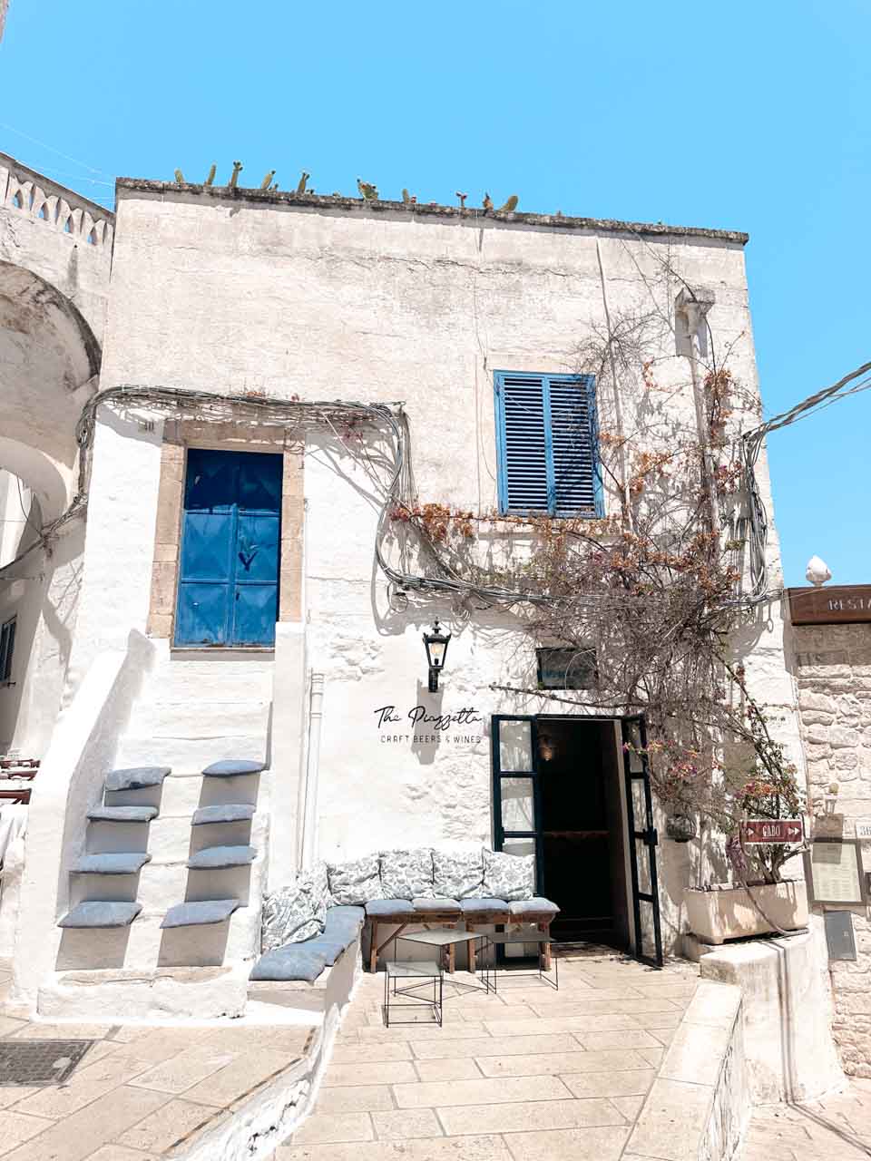 The Piazzetta spritz bar with blue shutters and vine-covered walls in Ostuni&rsquo;s old town