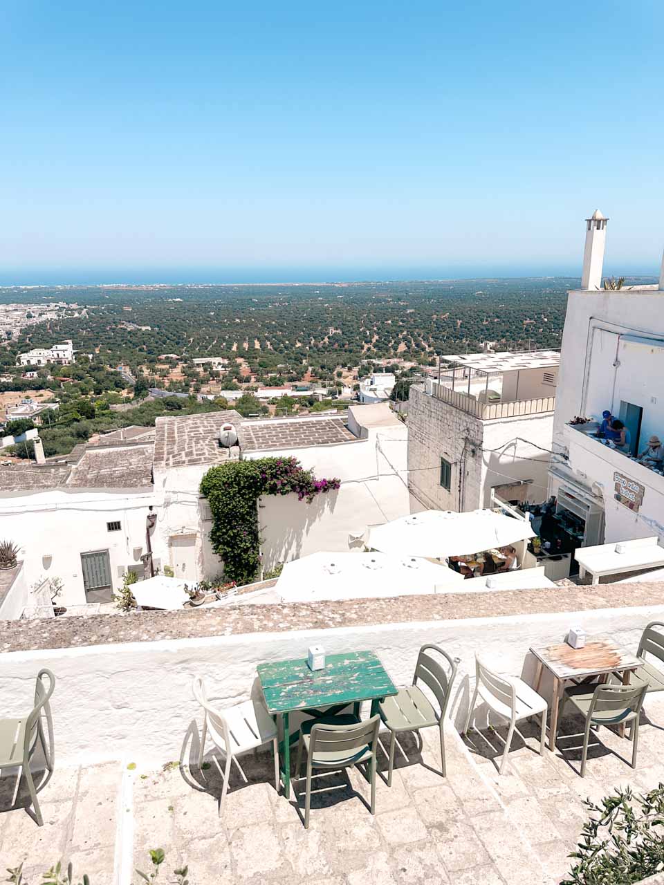 View over rooftops and olive groves towards the Adriatic Sea from Borgo Antico Bistrot in Ostuni, Italy