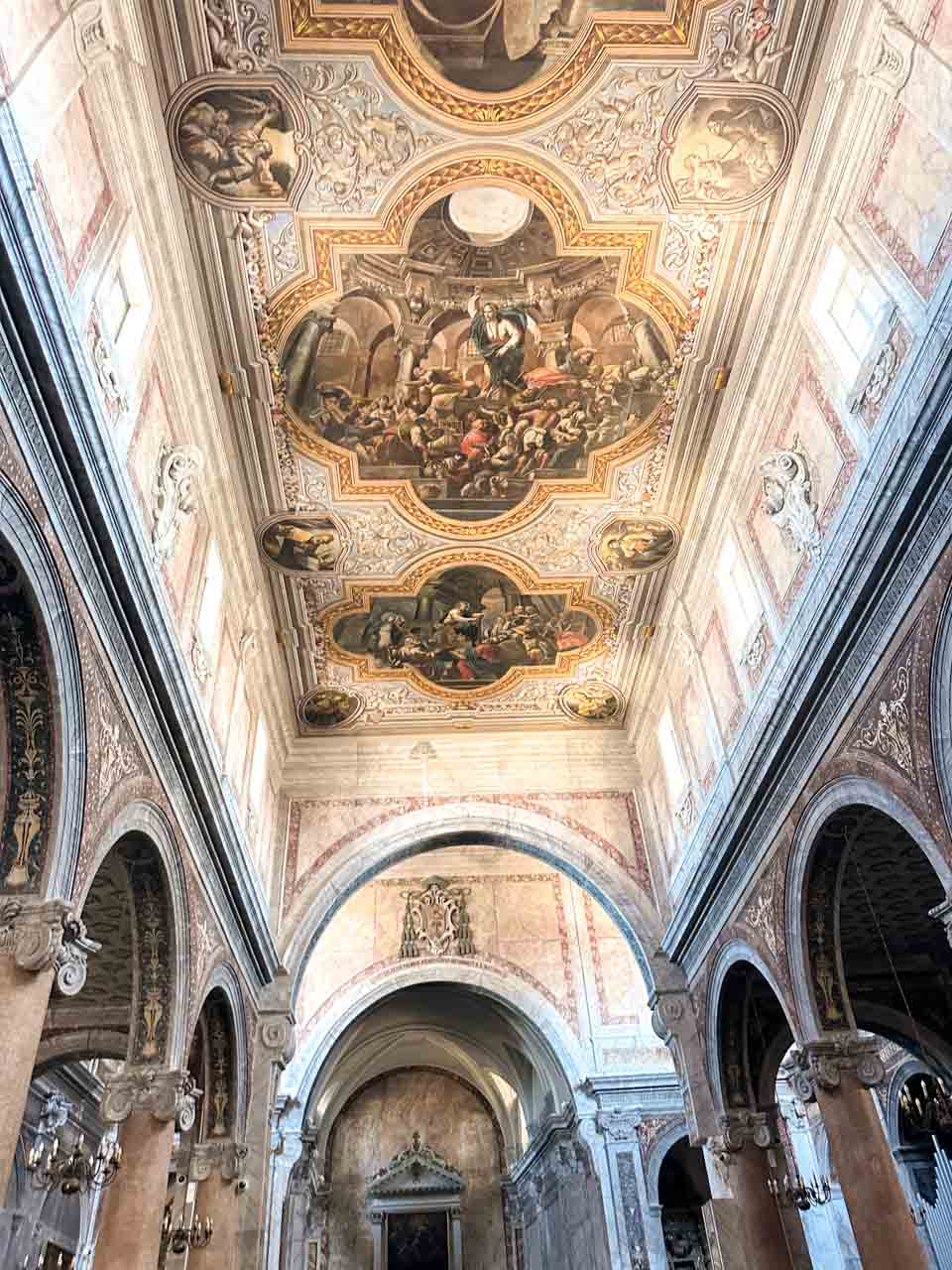 The ornate interior of Ostuni Cathedral with a frescoed ceiling and arches