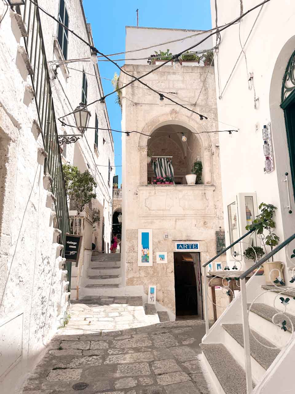 Charming street with stairs, balconies, and a small art shop in Ostuni old town