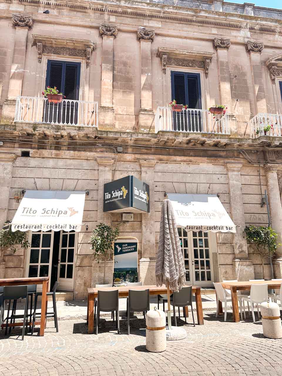 Outdoor tables in front of Tito Schipa restaurant with a stone facade in Ostuni, Italy