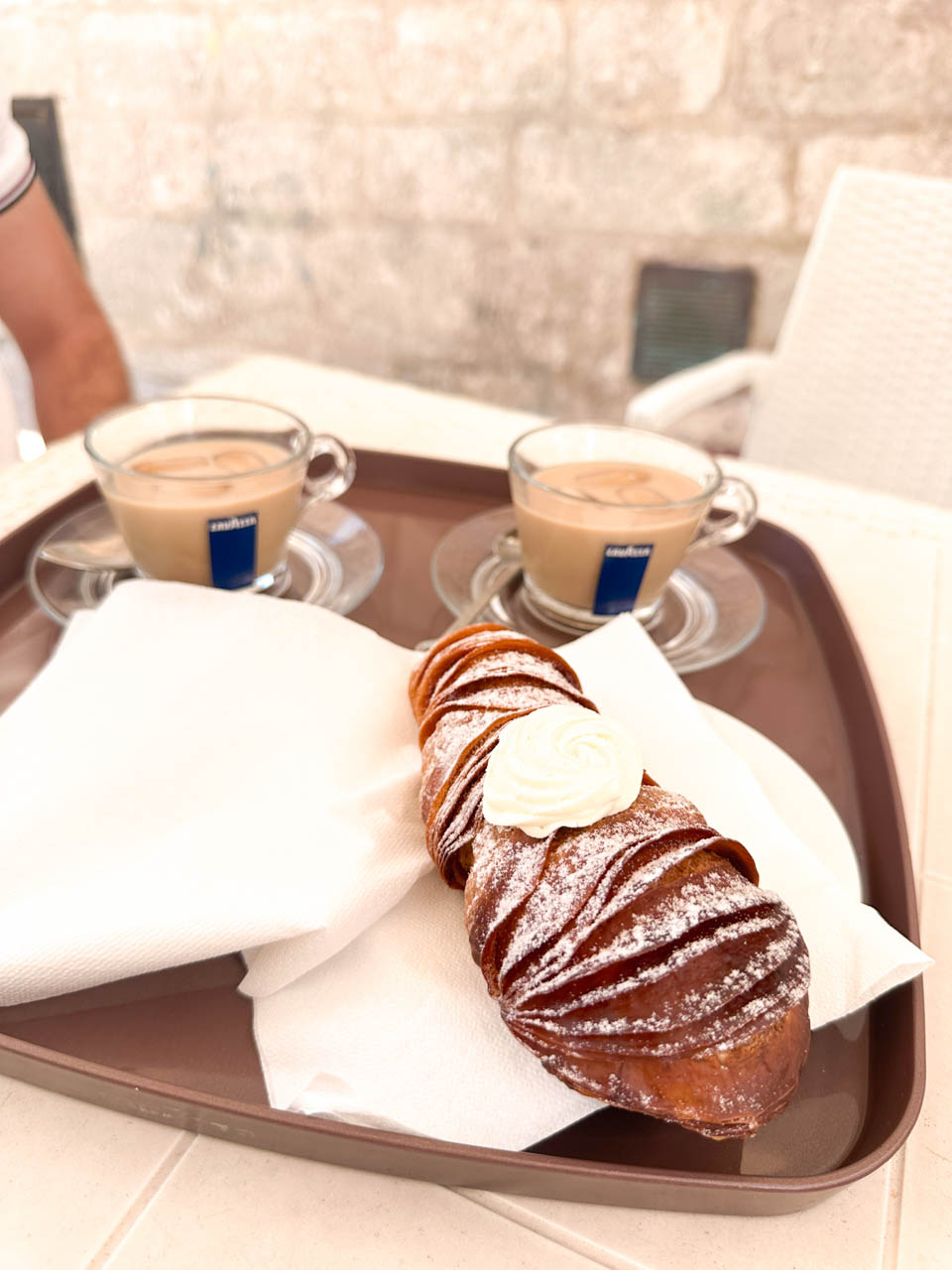 Coda d&rsquo;aragosta pastry with cream and two coffees served on a tray at Pasticceria da Pasquale in Ostuni, Italy