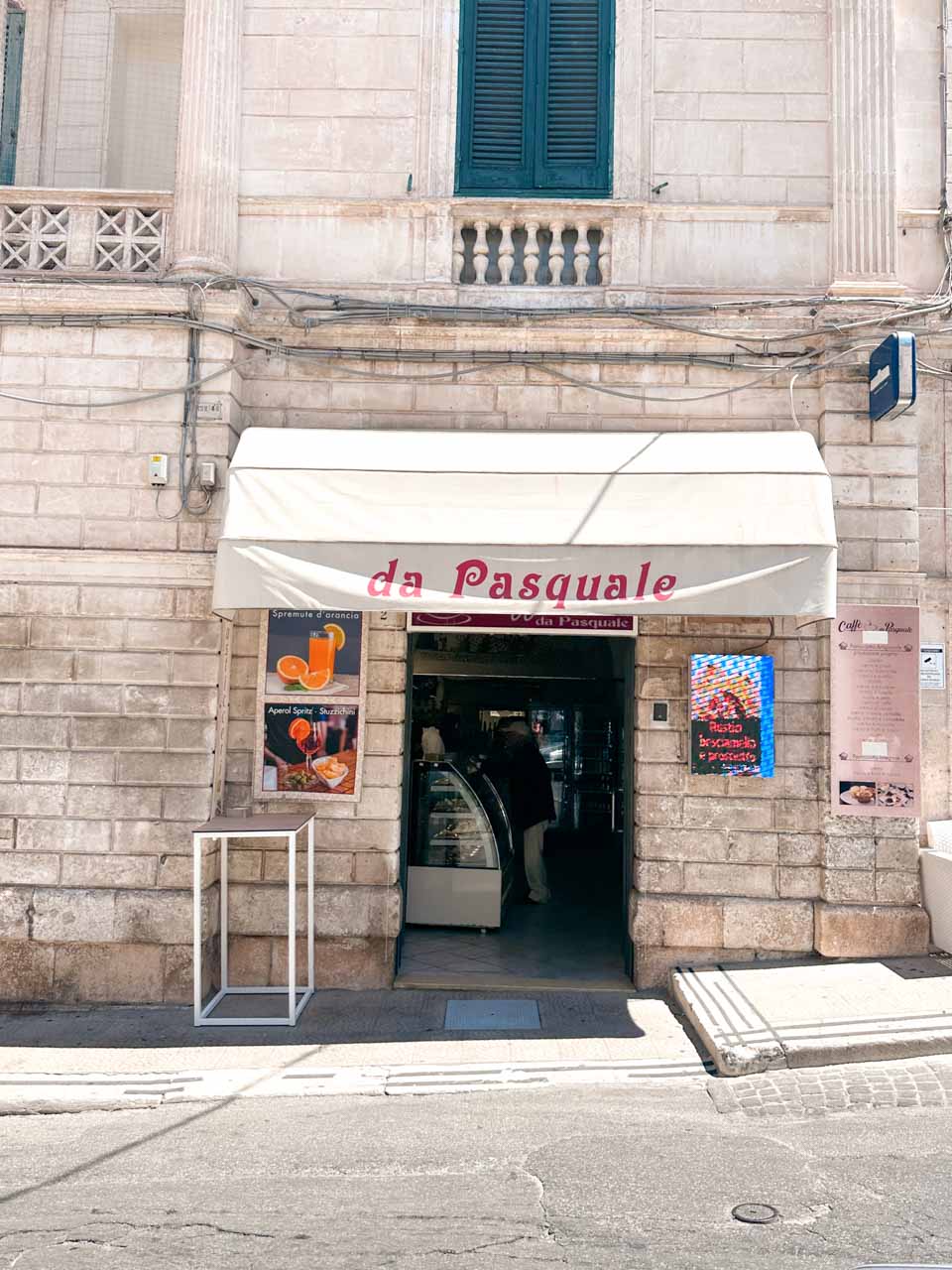 Entrance to Pasticceria da Pasquale with an awning and menu signs in Ostuni, Italy