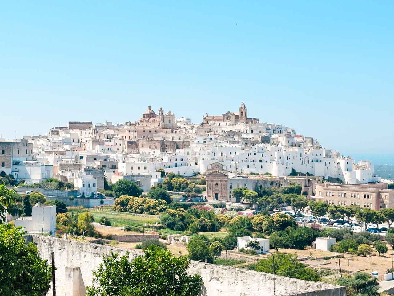 Panoramic view of Ostuni&rsquo;s whitewashed hilltop old town surrounded by greenery and countryside