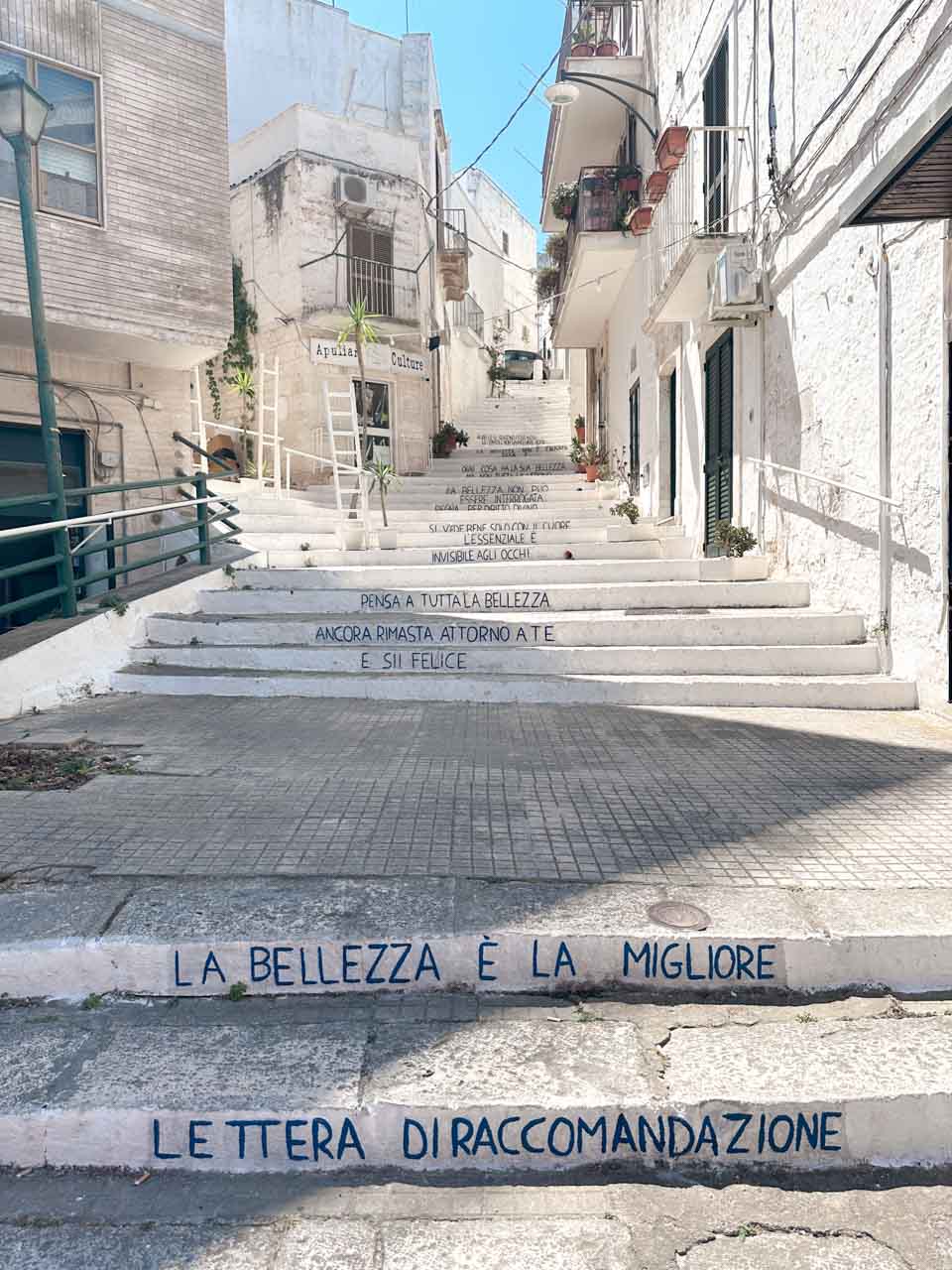 White staircase with Italian quotes painted on the steps in Ostuni, Italy