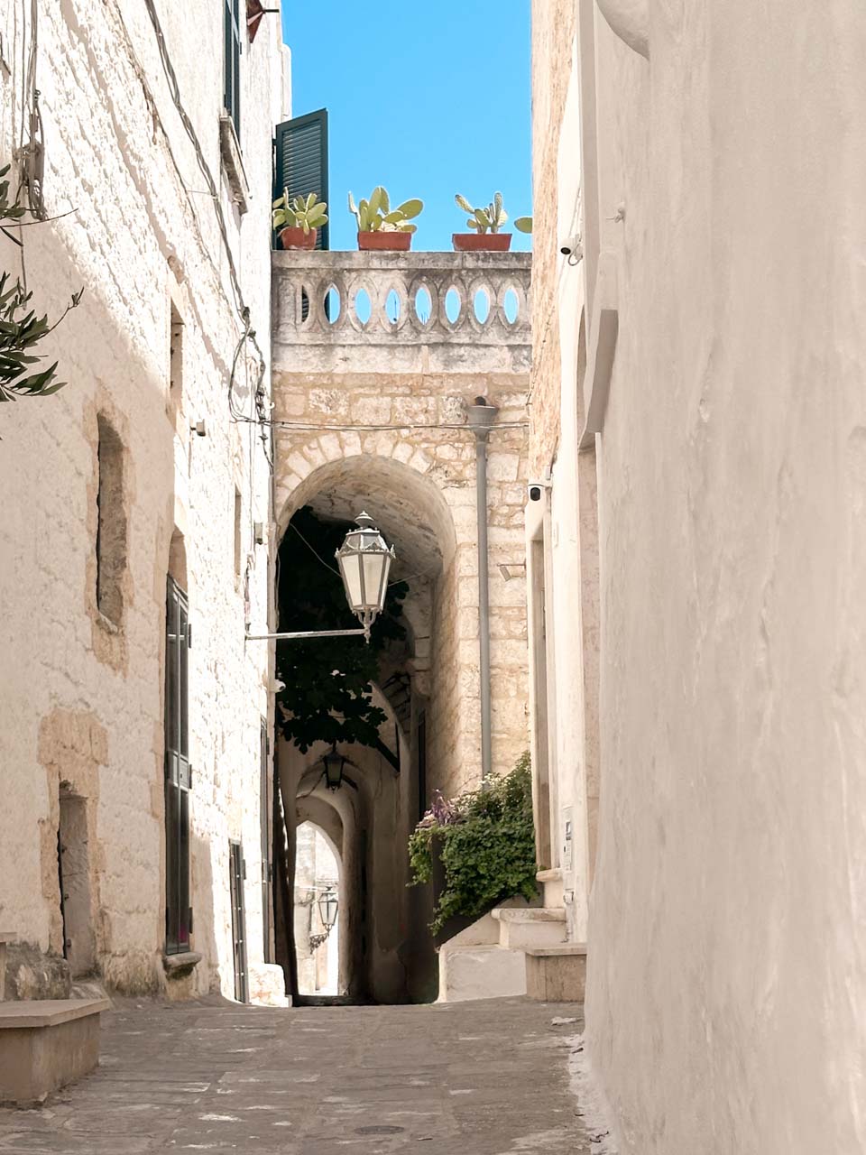 Narrow alley with an archway and a hanging lantern in Ostuni old town