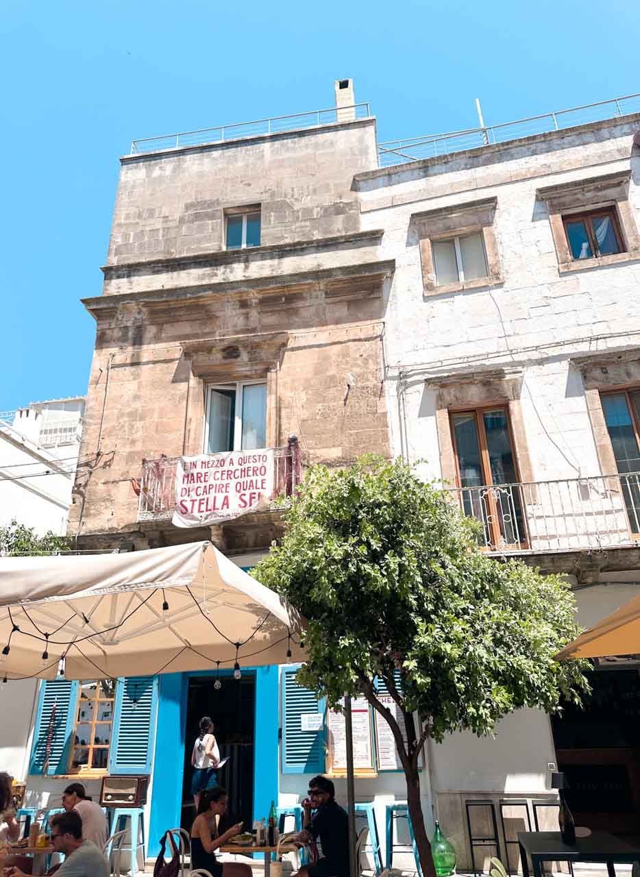 Street caf&eacute; with blue shutters and outdoor seating in Ostuni, Italy