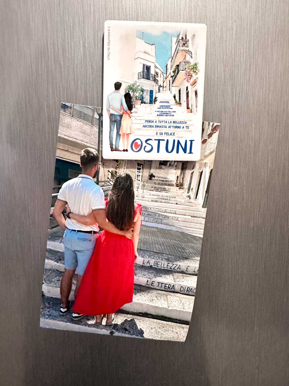 Souvenir magnet of a couple on the quote-covered stairs next to a photo recreating the same scene in Ostuni