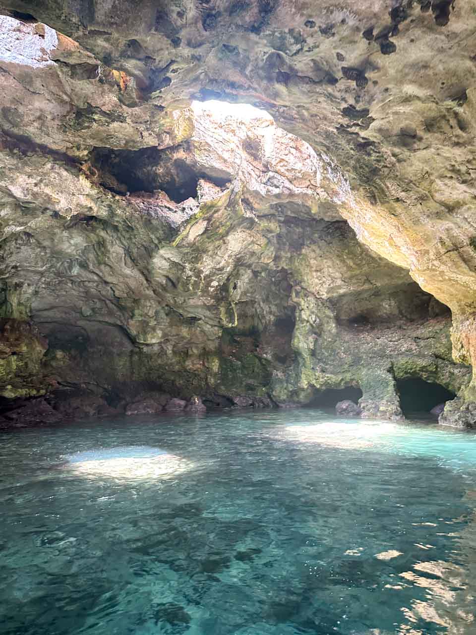 Rocky sea cave with sunlight reflecting on the water during a boat tour in Polignano a Mare, Italy