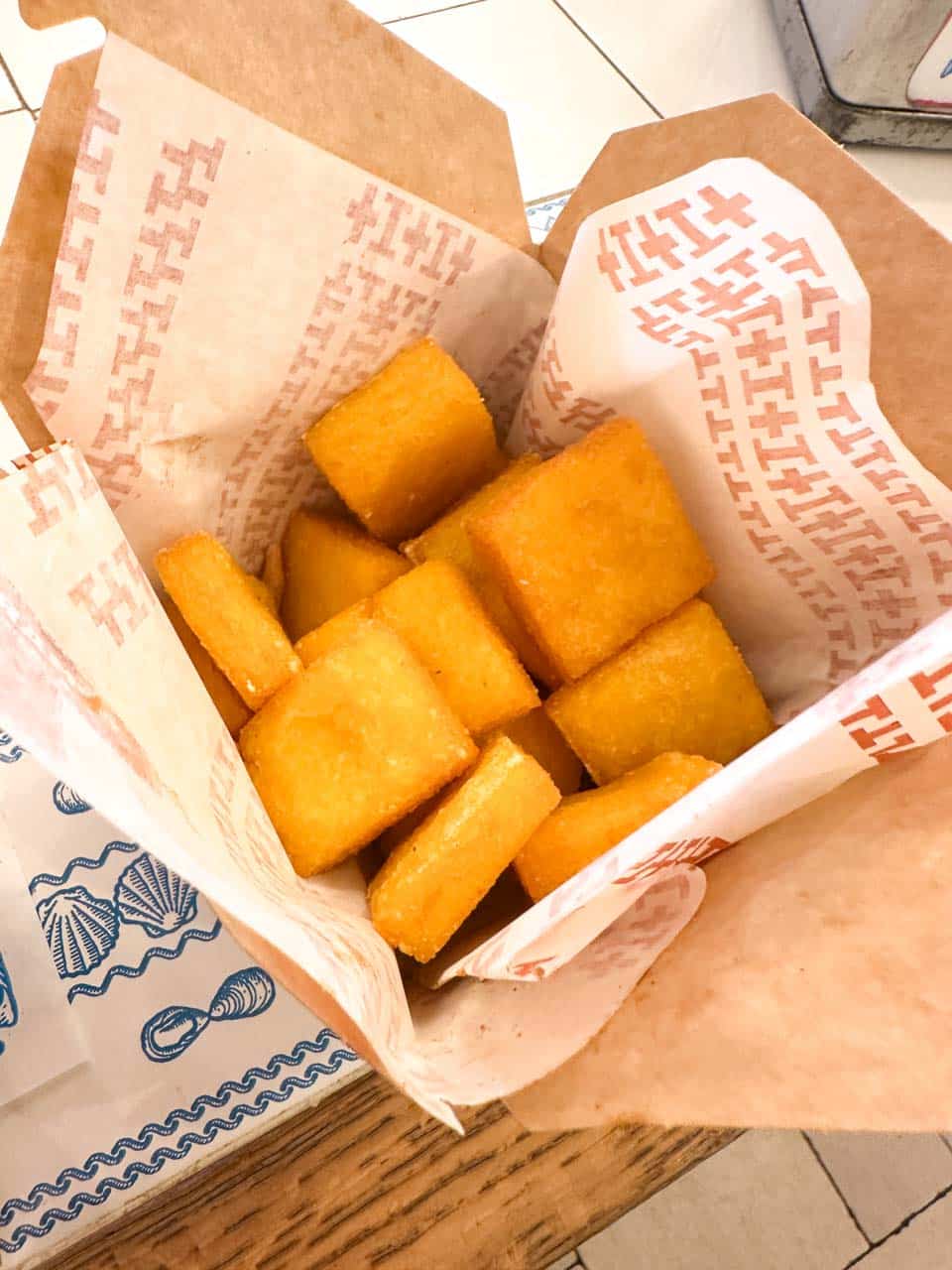 A seafood snack of fried polenta cubes served in paper at Pescaria in Polignano a Mare, Italy
