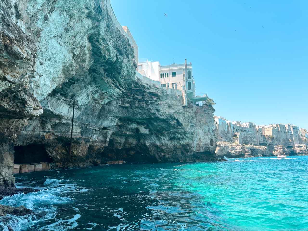 Cliffside houses above the sea, with caves below along the coast in Polignano a Mare, Italy