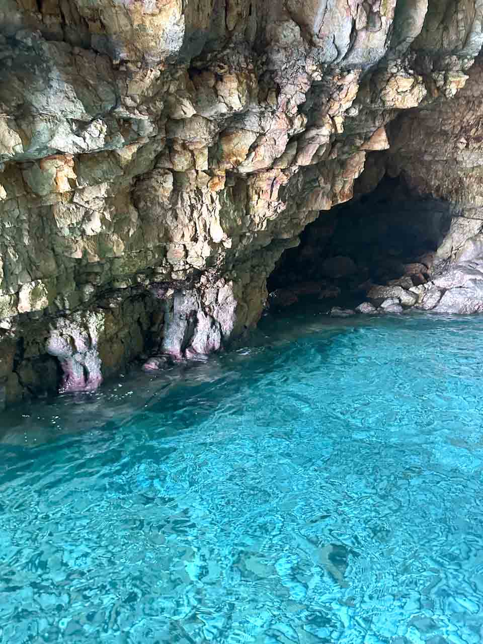 The inside of a rocky sea cave with clear turquoise water along the Polignano a Mare coastline