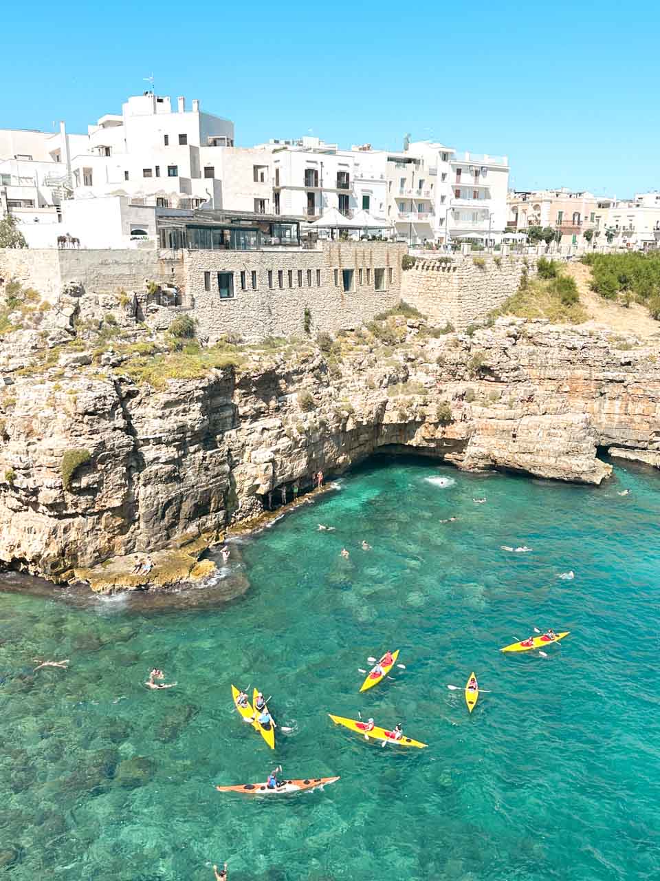 Kayakers in bright yellow boats near the Lama Monachile beach in Polignano a Mare, Italy