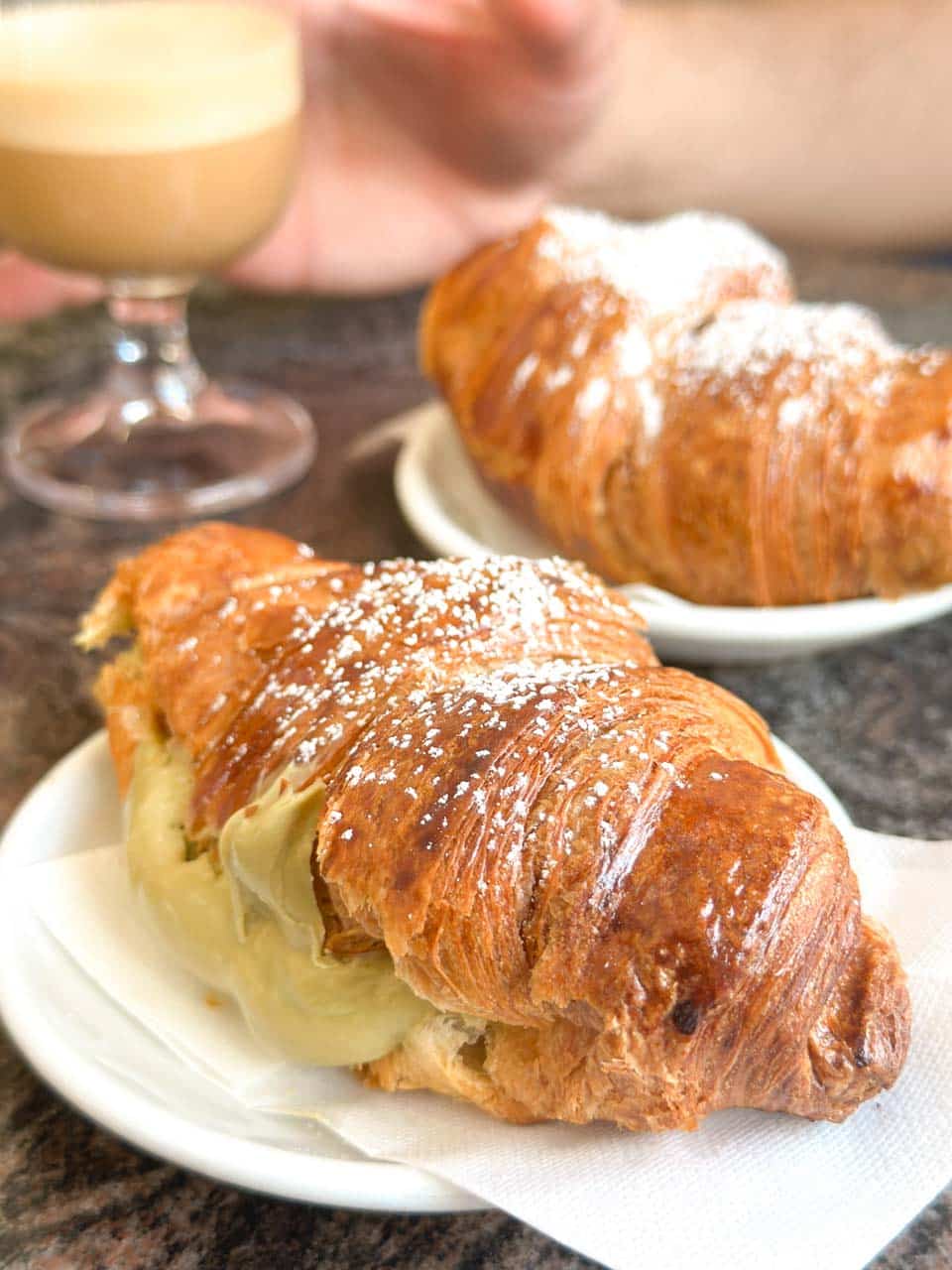 Two cream-filled croissants dusted with sugar served with coffee at The Super Mago del Gelo Mario Campanella in Polignano a Mare, Italy