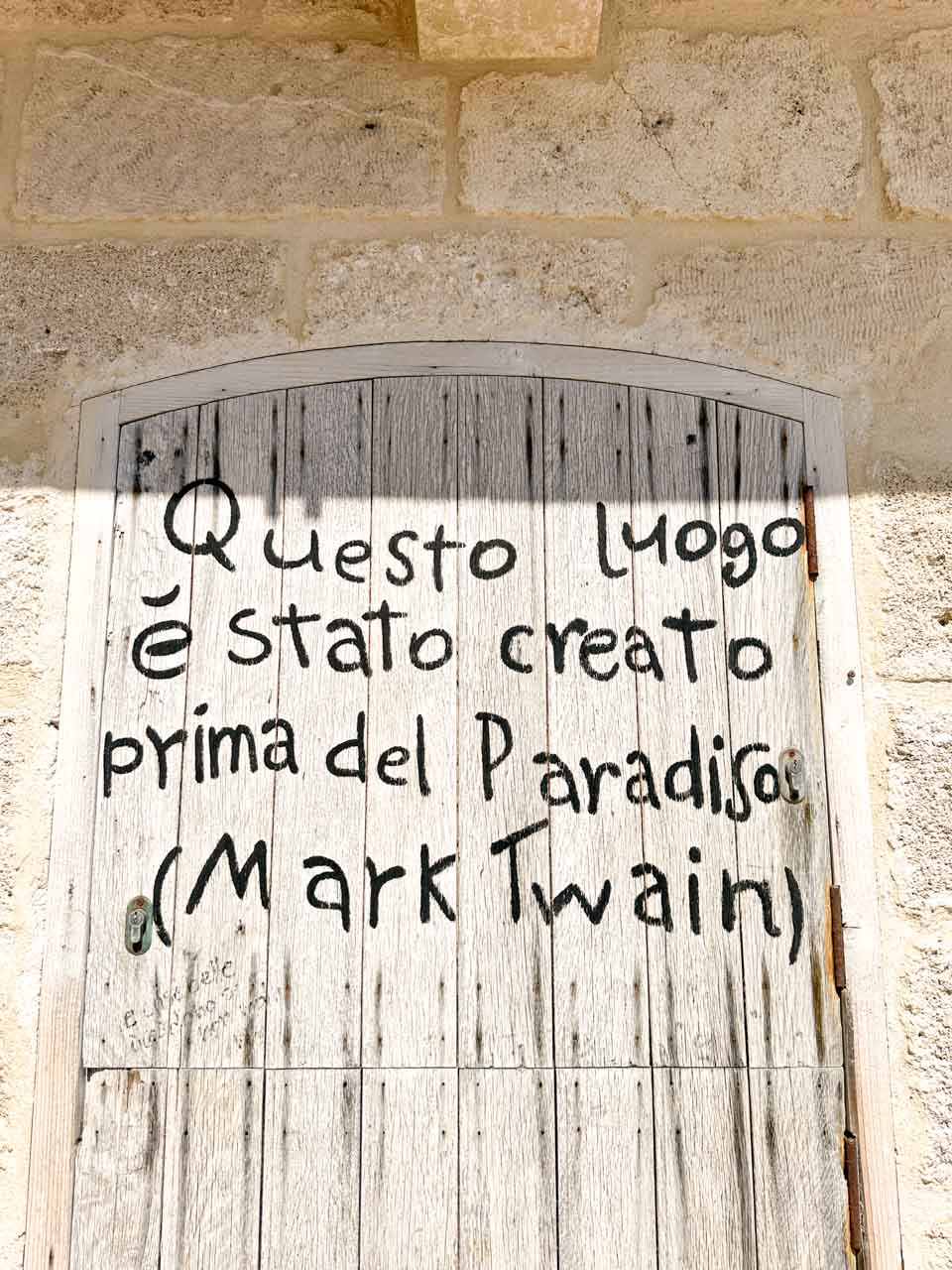 A wooden door with a handwritten quote attributed to Mark Twain in Polignano a Mare, Italy