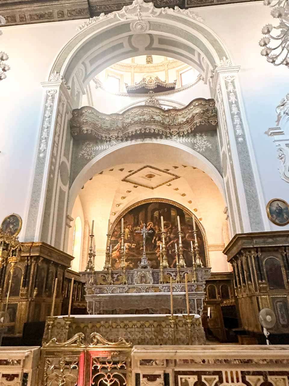Ornate church altar with candles, paintings, and decorative arches inside the Church of Saint Mary of the Assumption in Polignano a Mare