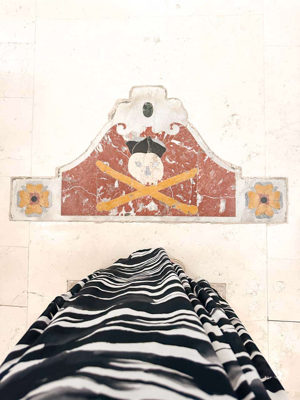 View from above of a tiled floor with a decorative skull and crossed bones motif at the Church of Saint Mary of the Assumption in Polignano a Mare