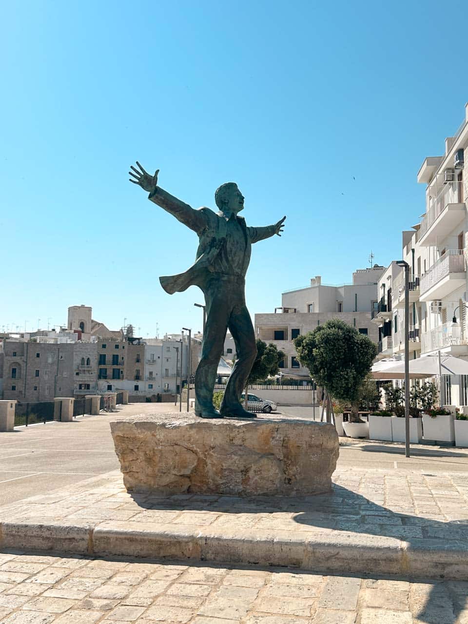 Statue of Domenico Modugno with outstretched arms in Polignano a Mare, Italy