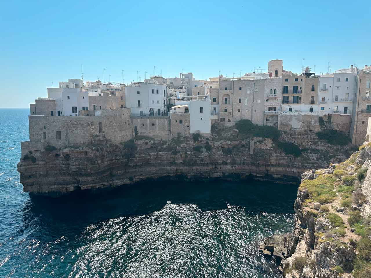 White buildings perched on cliffs above the sea in Polignano a Mare, Italy