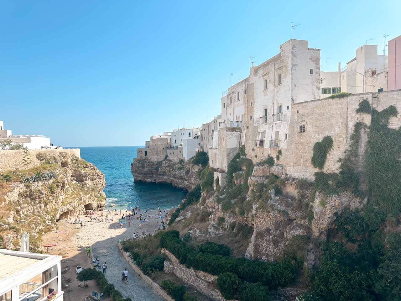 View of the Lama Monachile beach and cliffs with white buildings above in Polignano a Mare