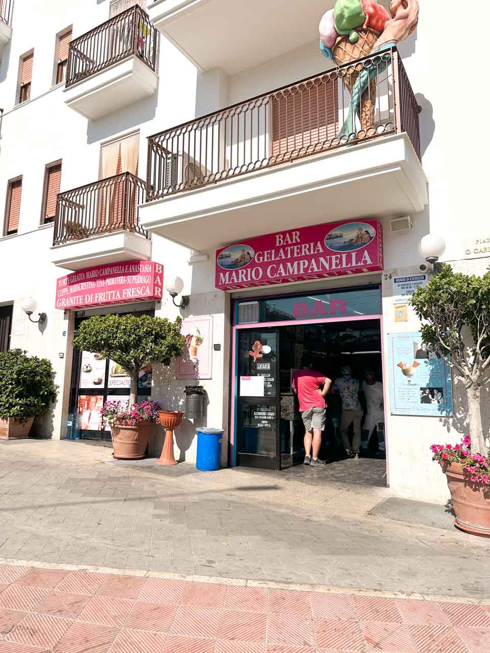 Exterior of Bar Gelateria Mario Campanella with a large gelato sculpture on a balcony in Polignano a Mare