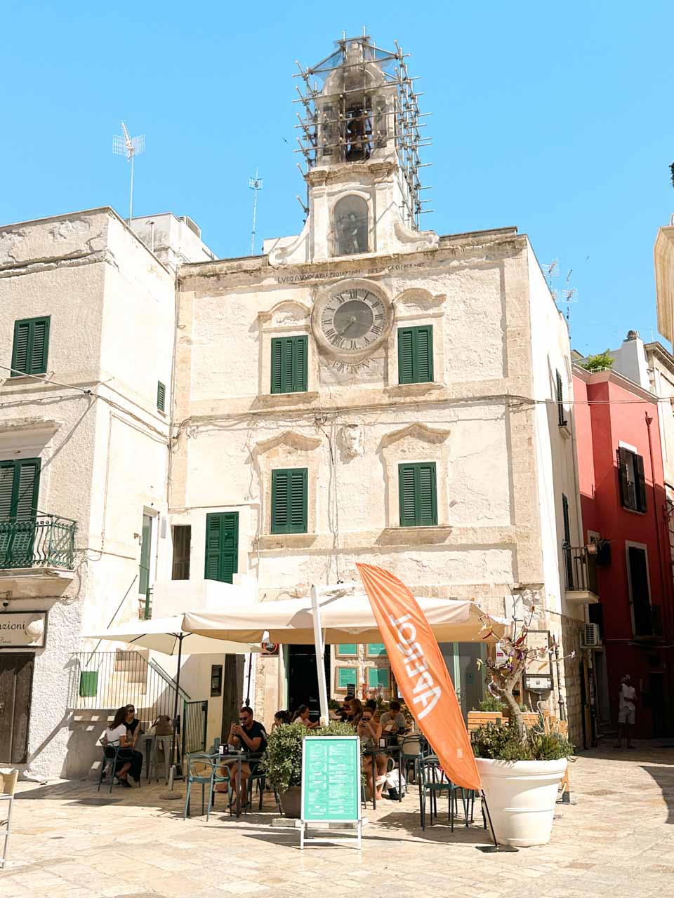 Palazzo dell&rsquo;Orologio with outdoor caf&eacute; seating in a square in Polignano a Mare